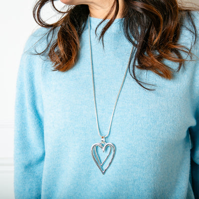 The Amara Long Necklace in silver featuring two heart pendants layered over each other