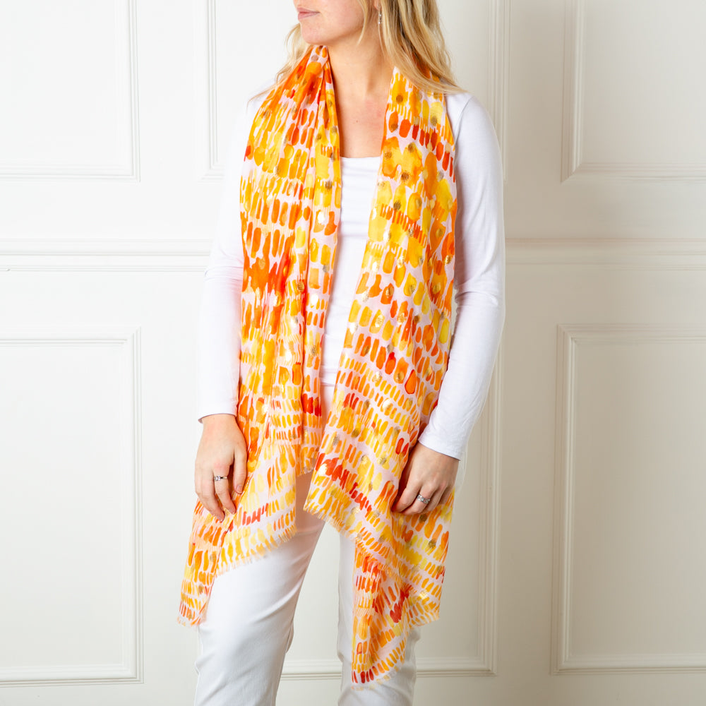 The orange Bora Bora Scarf featuring a beautiful spotty block print pattern with hints of gold foil dotted throughout
