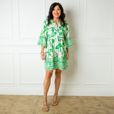 The green Florence Drawstring Dress with a tie tassel detail and buttons down the front in a bold floral pattern 