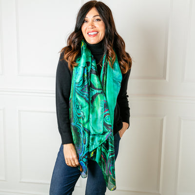 The green oil spill silk scarf pictured draped over a simple black polo neck jumper.