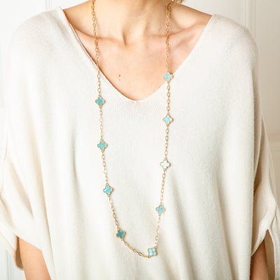 The Ivy Necklace in gold with blue sparkly clover pendants spread along the chain