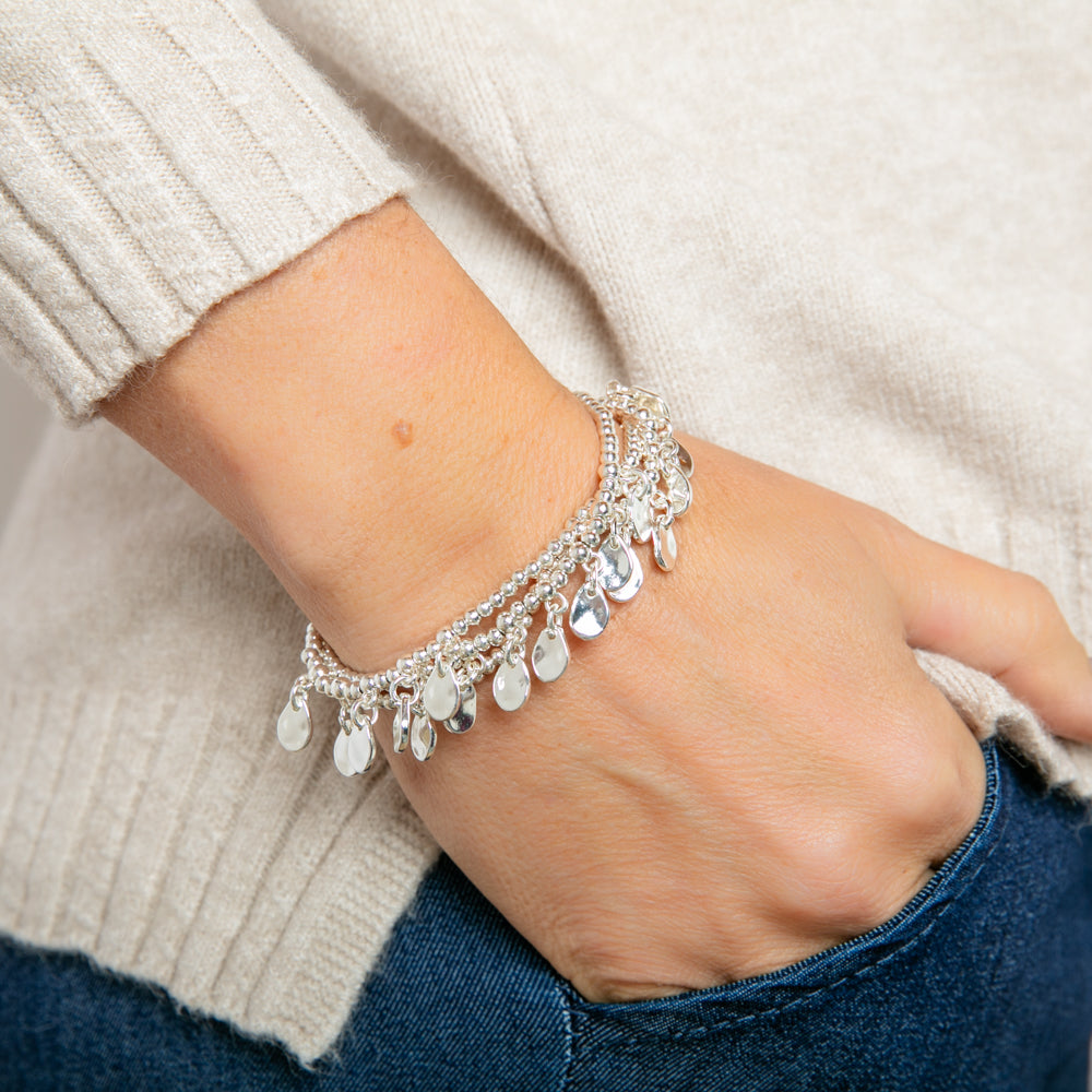 Model showcases the Larni Bracelet - a women's silver bracelet set with multiple pendants to one side. 3 layers are shown, joined together at one singular point.