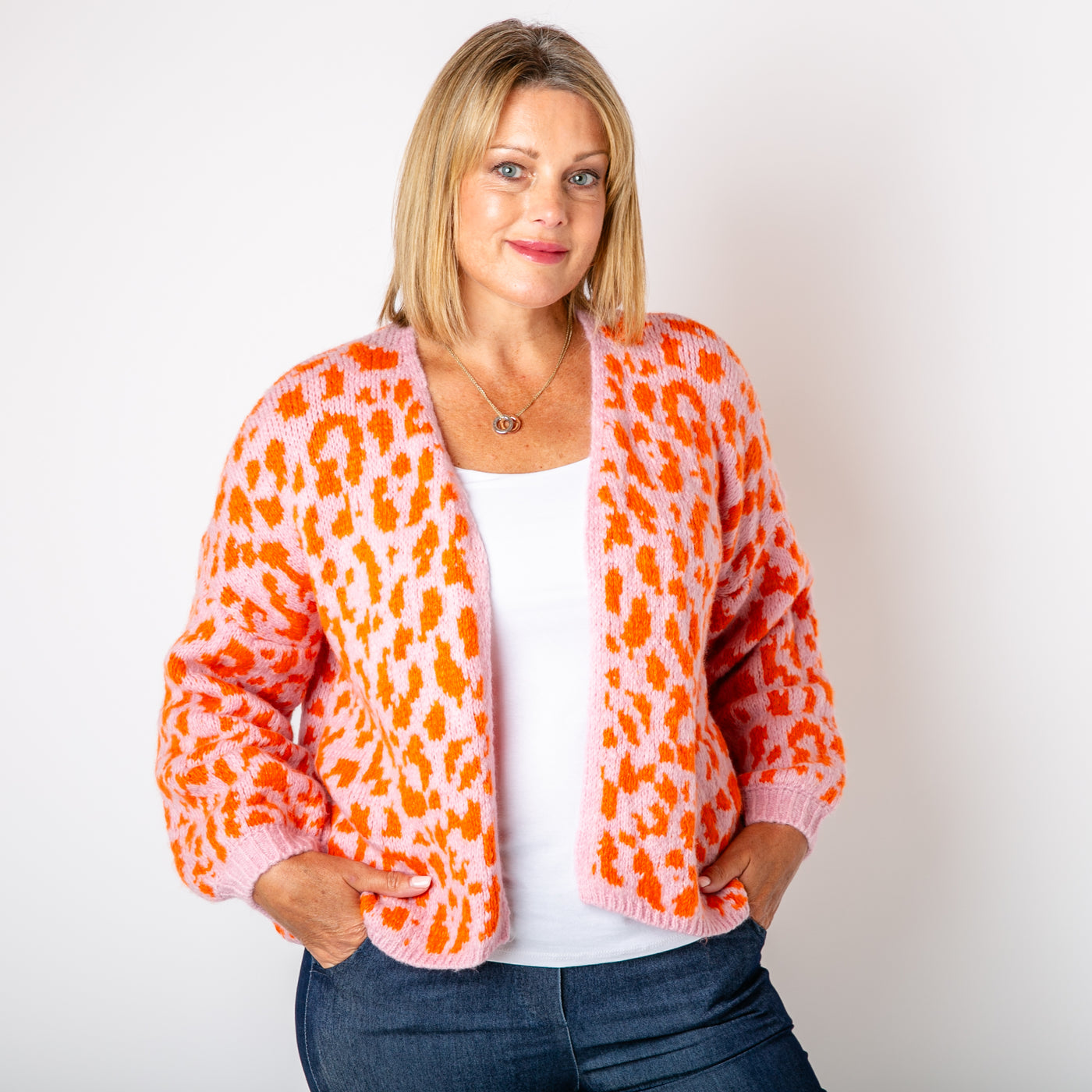 The orange Leopard Print Cardigan paired with a baby pink background 