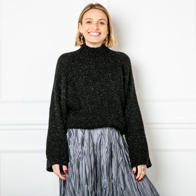 The metallic thread jumper in black, shown in an image with the crinkle skirt and gold earrings. 