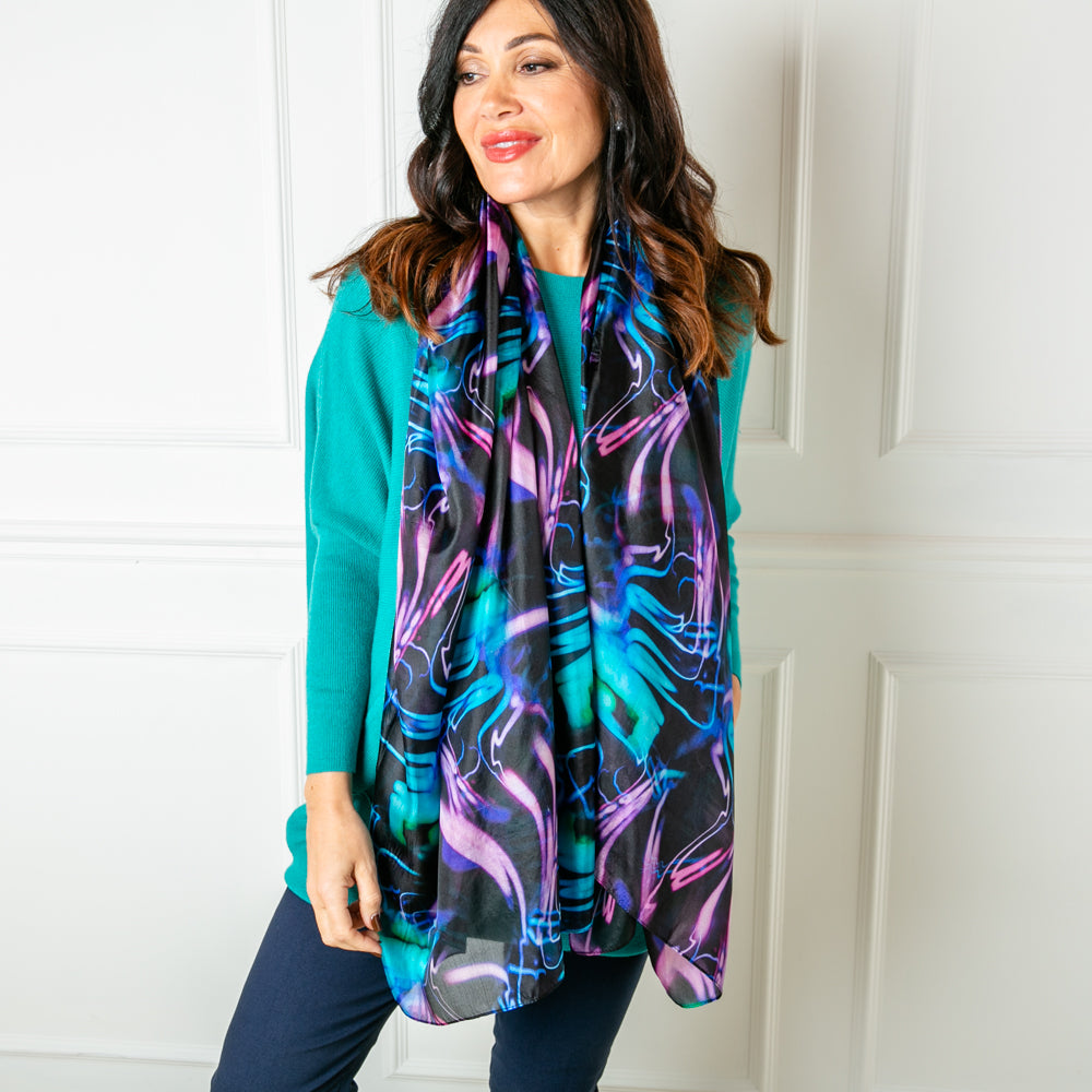 The Neon Lights Silk Scarf featuring a bold print with shades of black purple and blue