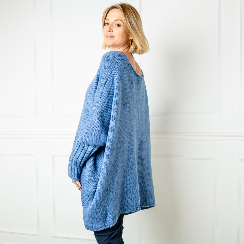 A side shot of the denim colour oversized jumper. It has a round neckline and fitted cuff sleeves.