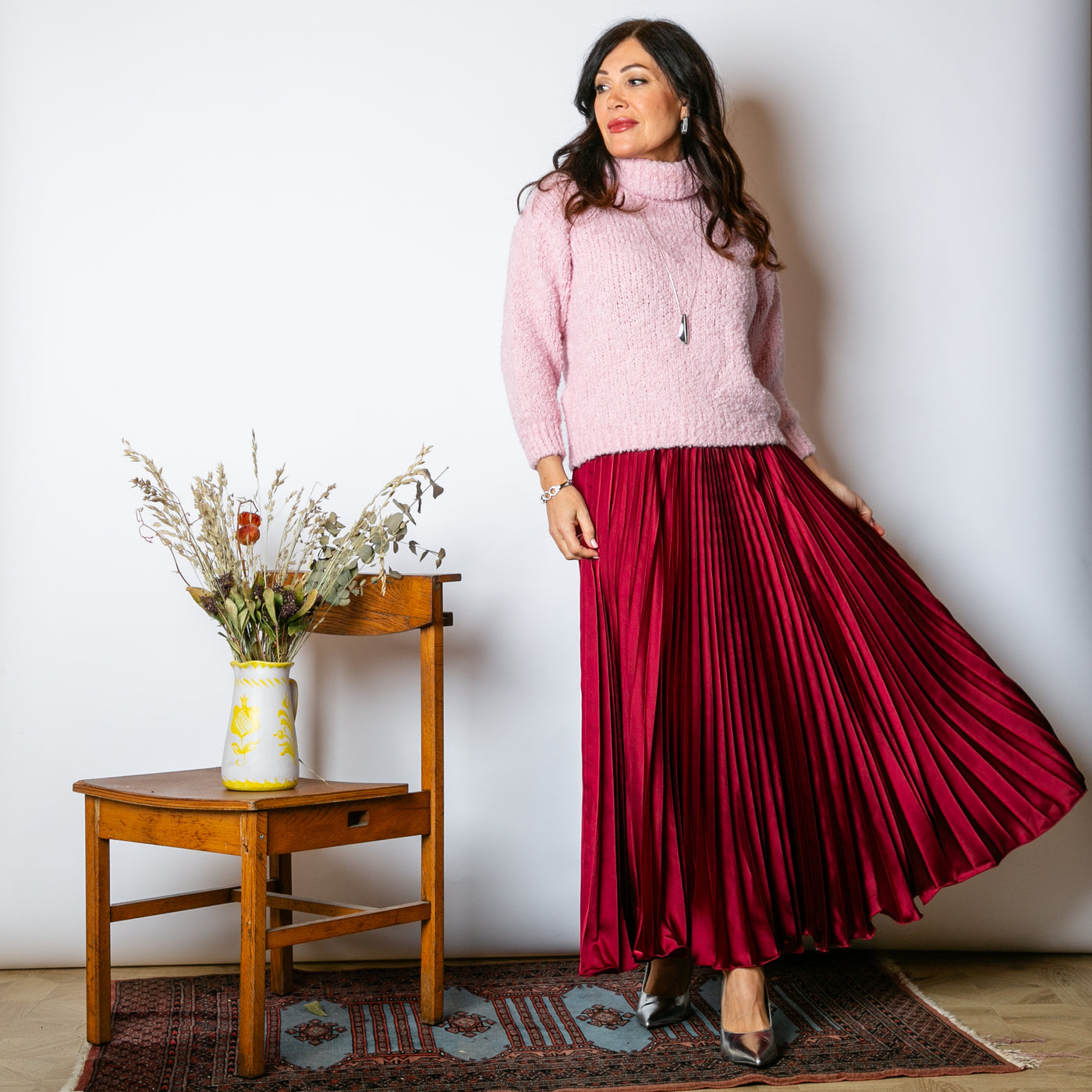 The Pleated Cocktail Skirt in burgundy red made from an elegant material with a satin finish