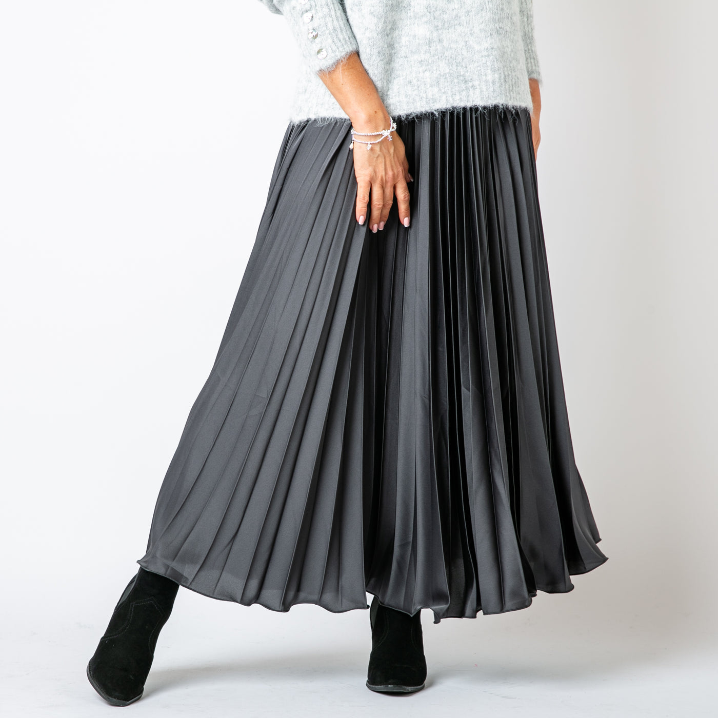 The Pleated Cocktail Skirt in charcoal grey made from an elegant material with a satin finish