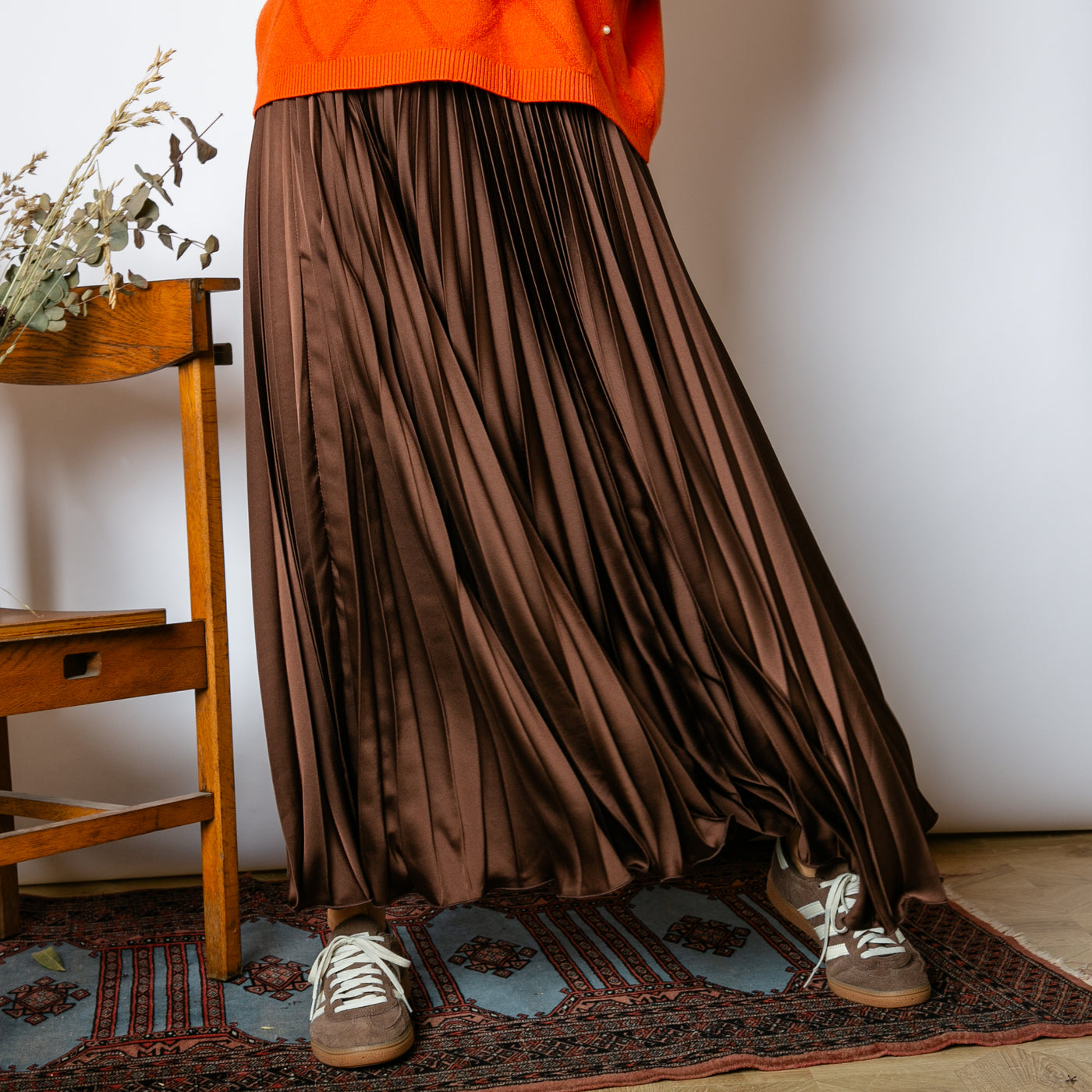 The Pleated Cocktail Skirt in chocolate brown made from an elegant material with a satin finish