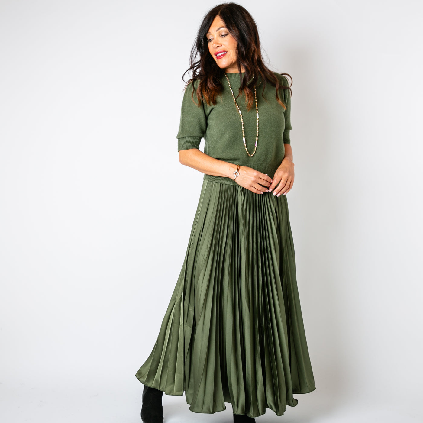 The Pleated Cocktail Skirt in olive green made from an elegant material with a satin finish