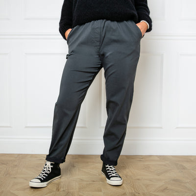 Plus size stretch trousers in charcoal grey with pockets on either side. The bottom hem can be rolled up to any length
