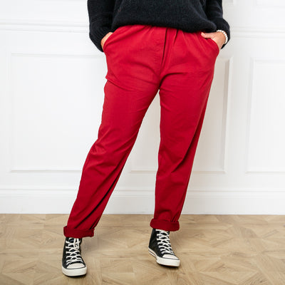 Plus size stretch trousers in dark red with pockets on either side. The bottom hem can be rolled up to any length