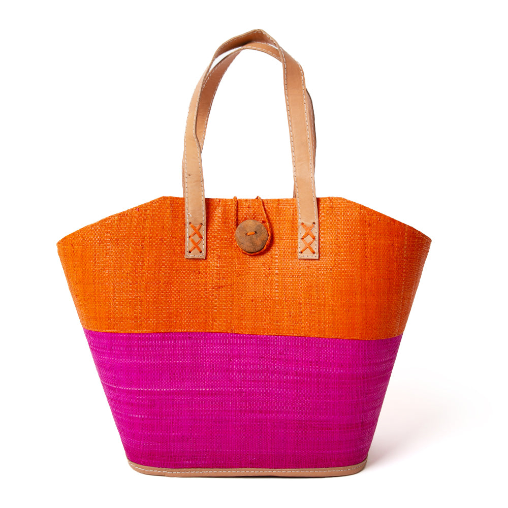 The Raffia Shopping Basket in orange and pink with a wooden button fastening detail at the top