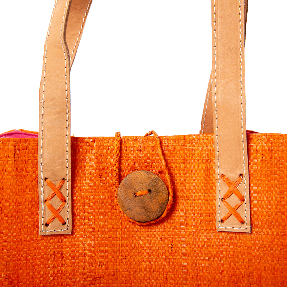 The Raffia Shopping Basket in orange and pink with leather handles and a cotton inner lining