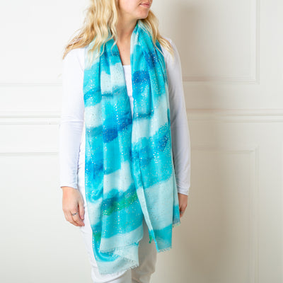The blue Reef Scarf featuring a beautiful gentle watercolour effect striped pattern 