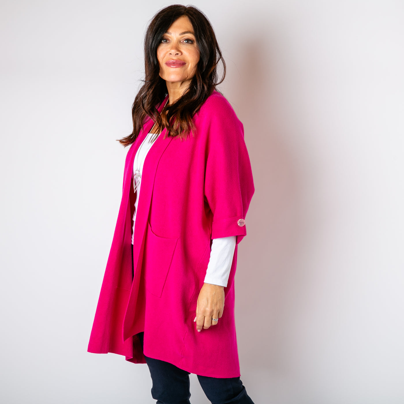 The fuchsia pink Shawl Button Cardigan with pockets on either side of the hip