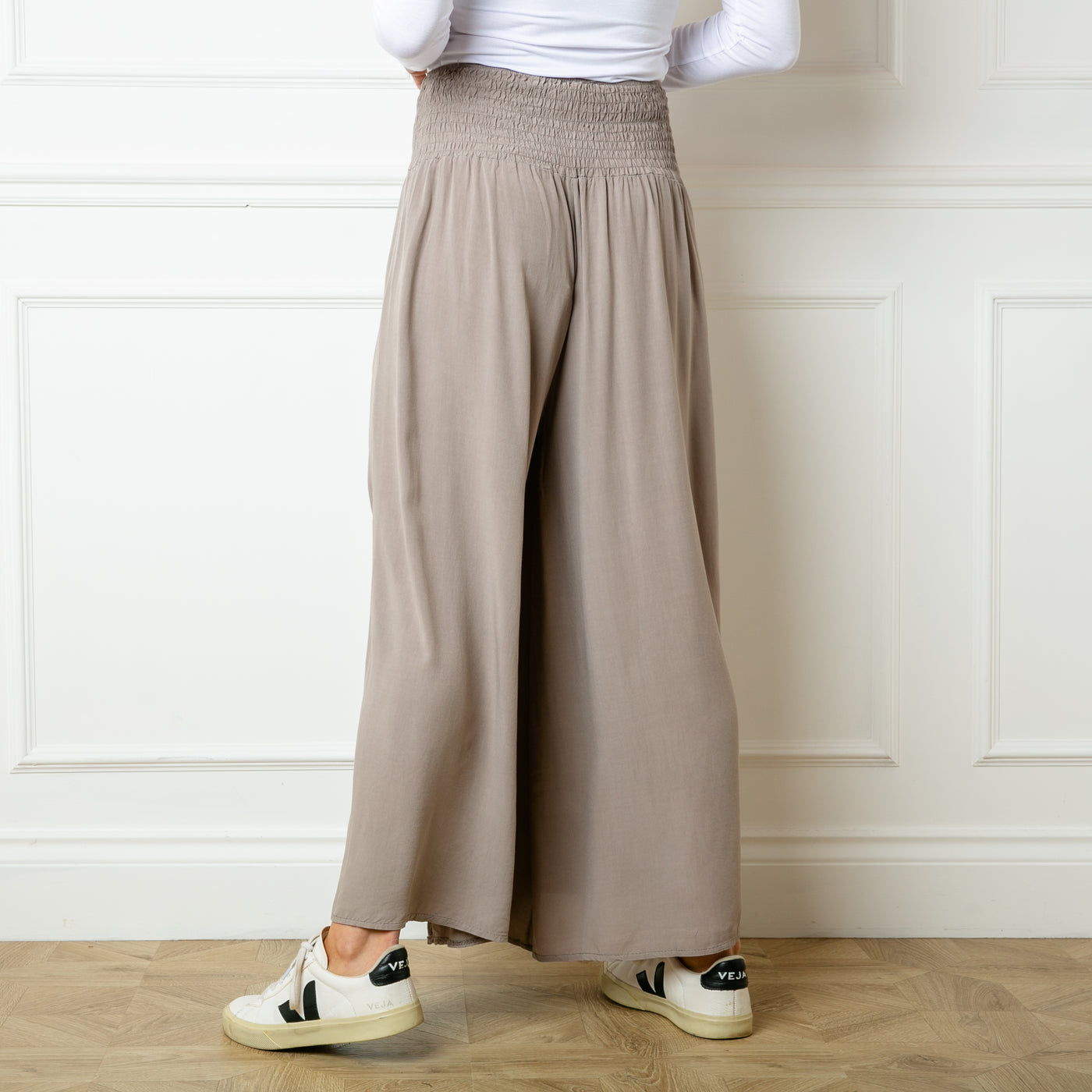 The taupe brown Shirred waist wide leg trousers featuring a wide, stretchy elasticated waistband