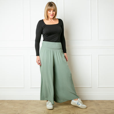 The sage green Shirred waist wide leg trousers featuring a wide, stretchy elasticated waistband