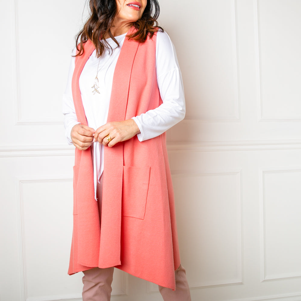 The Sleeveless Cardigan in coral orange pink with side pockets for added comfort