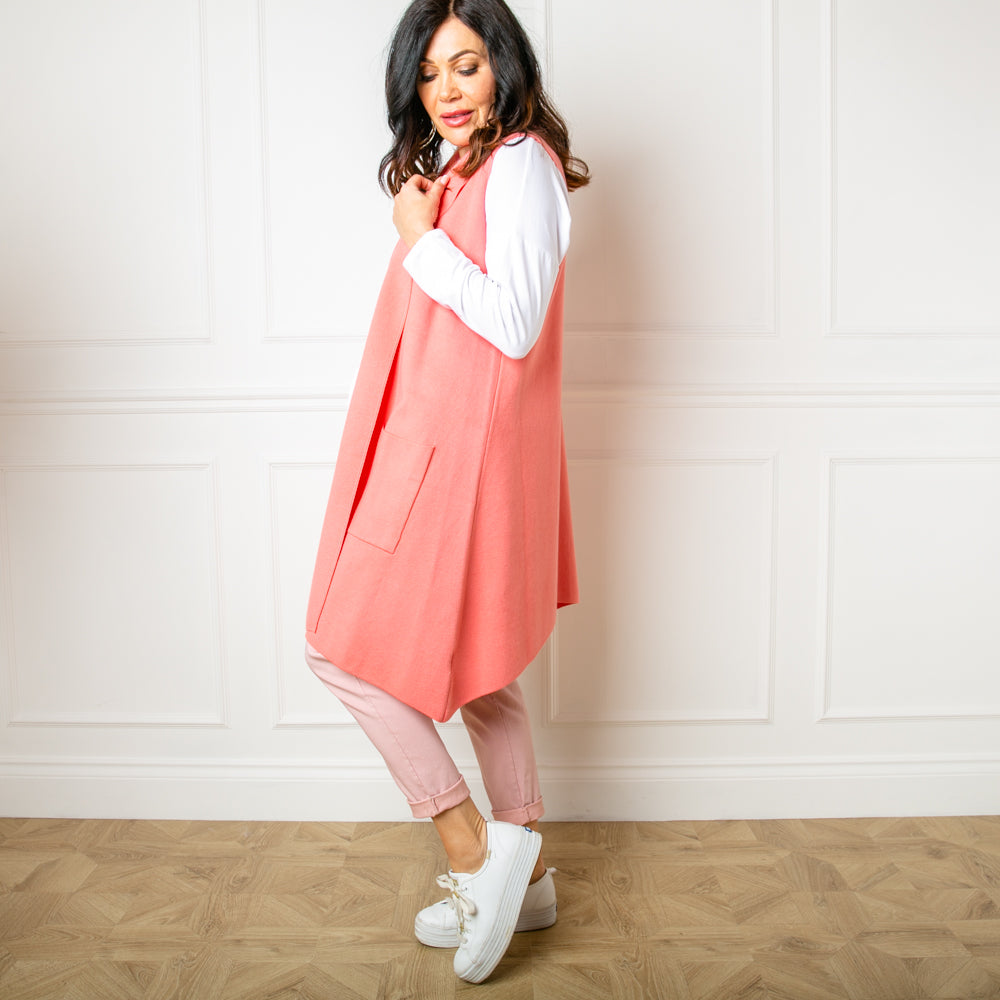 The Sleeveless Cardigan in coral pink orange which falls to just above the knee