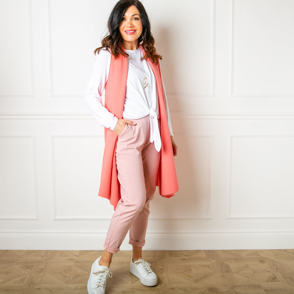 The Sleeveless cardigan in coral pink orange which is great for layering and perfect for summer