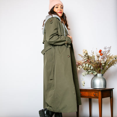 The khaki green Trench Coat With Hood with pockets on either side of the hip