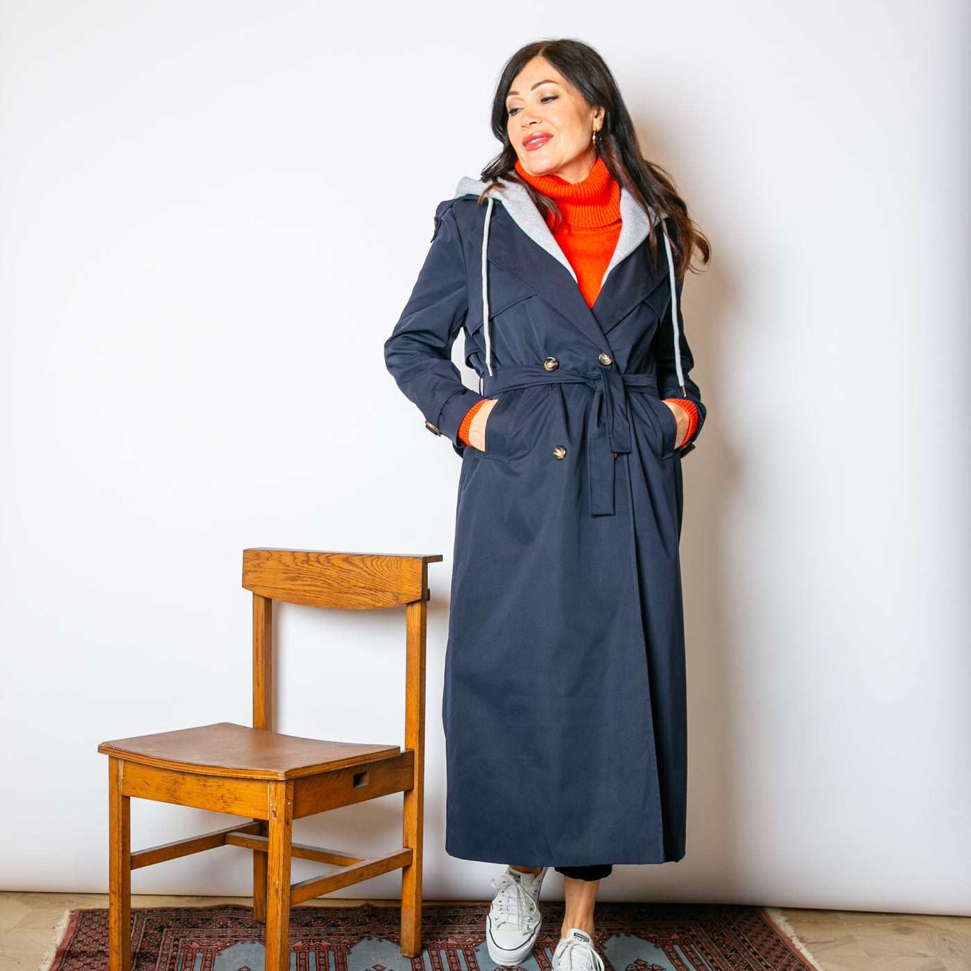 The navy blue Trench Coat With Hood with pockets on either side of the hip