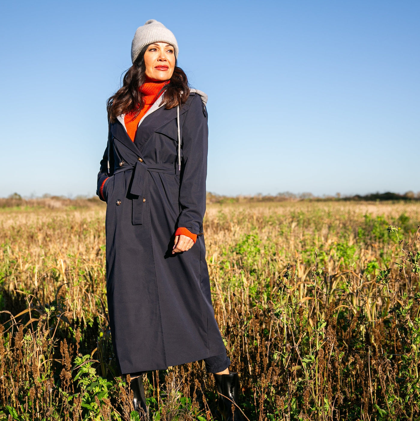 The navy blue Trench Coat With Hood that has long sleeves that have buckles on the cuffs.