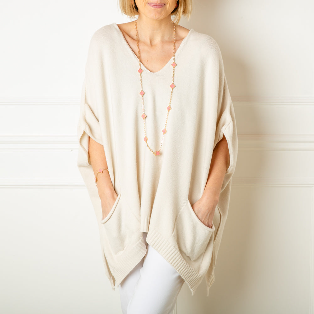 The oatmeal cream V Neck Pocket Poncho in a relaxed silhouette made from a fine knitted material