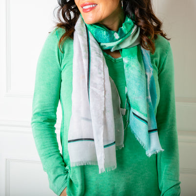 The Cairo scarf in green, worn on a model, wrapped around the neck 