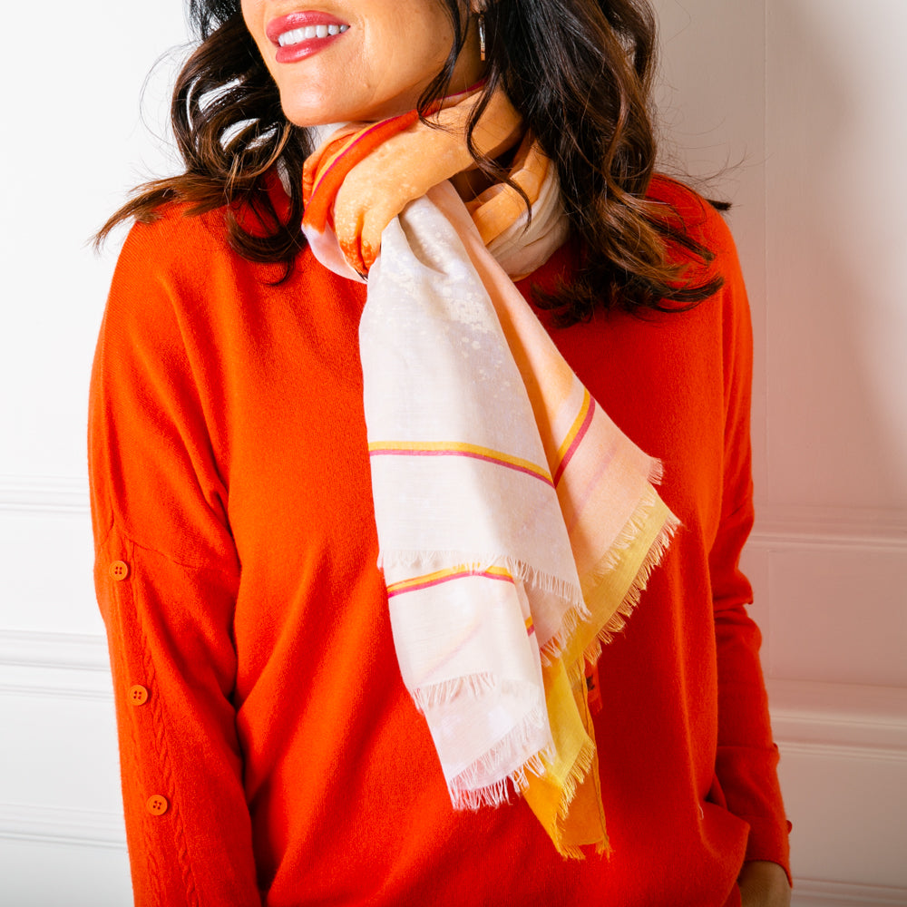 The Cairo scarf in orange, worn on a model, wrapped around the neck