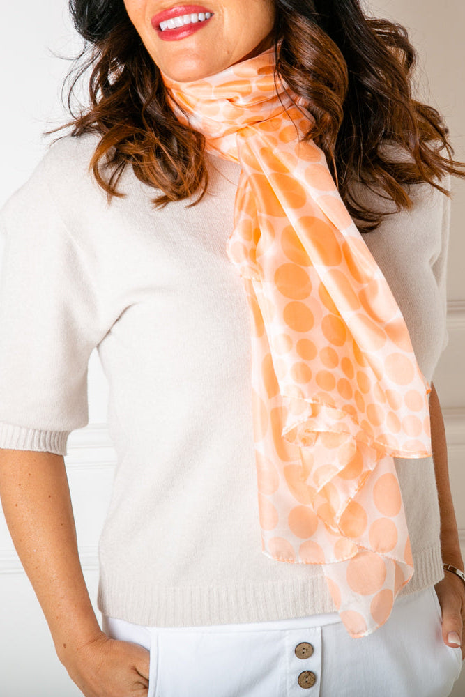 The Coral Spot silk Scarf worn by a model looped around the neck