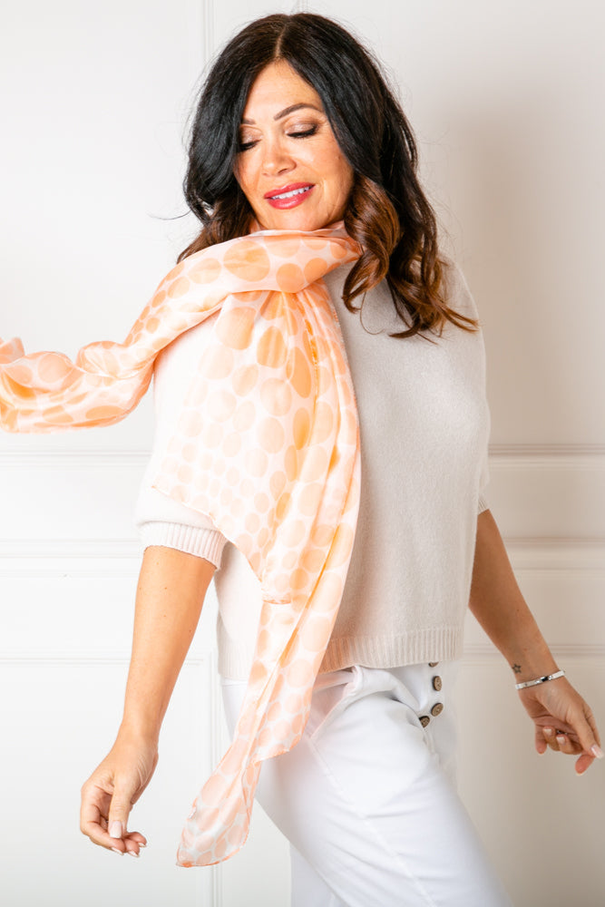 The Coral Spot Silk Scarf worn by a model, loosely over one shoulder 