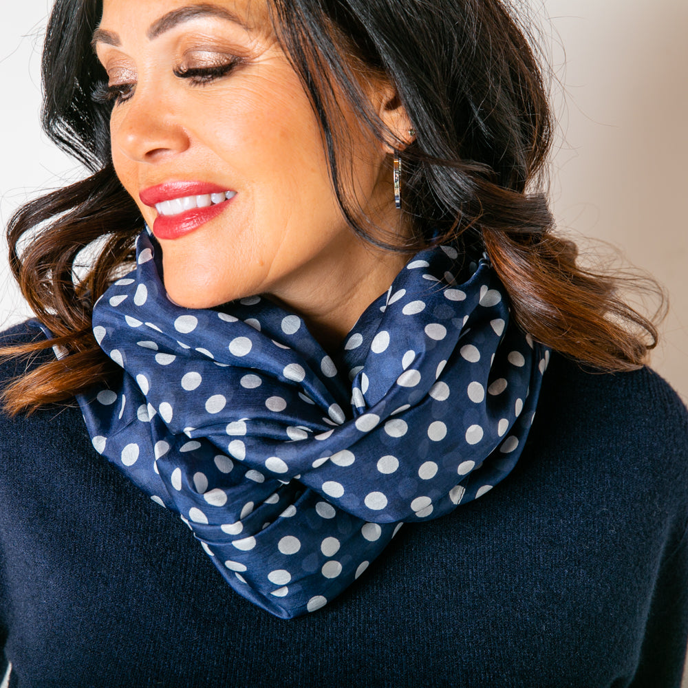 The Navy Polka Dot Silk Scarf worn by our model wrapped around the neck and tied at the back 
