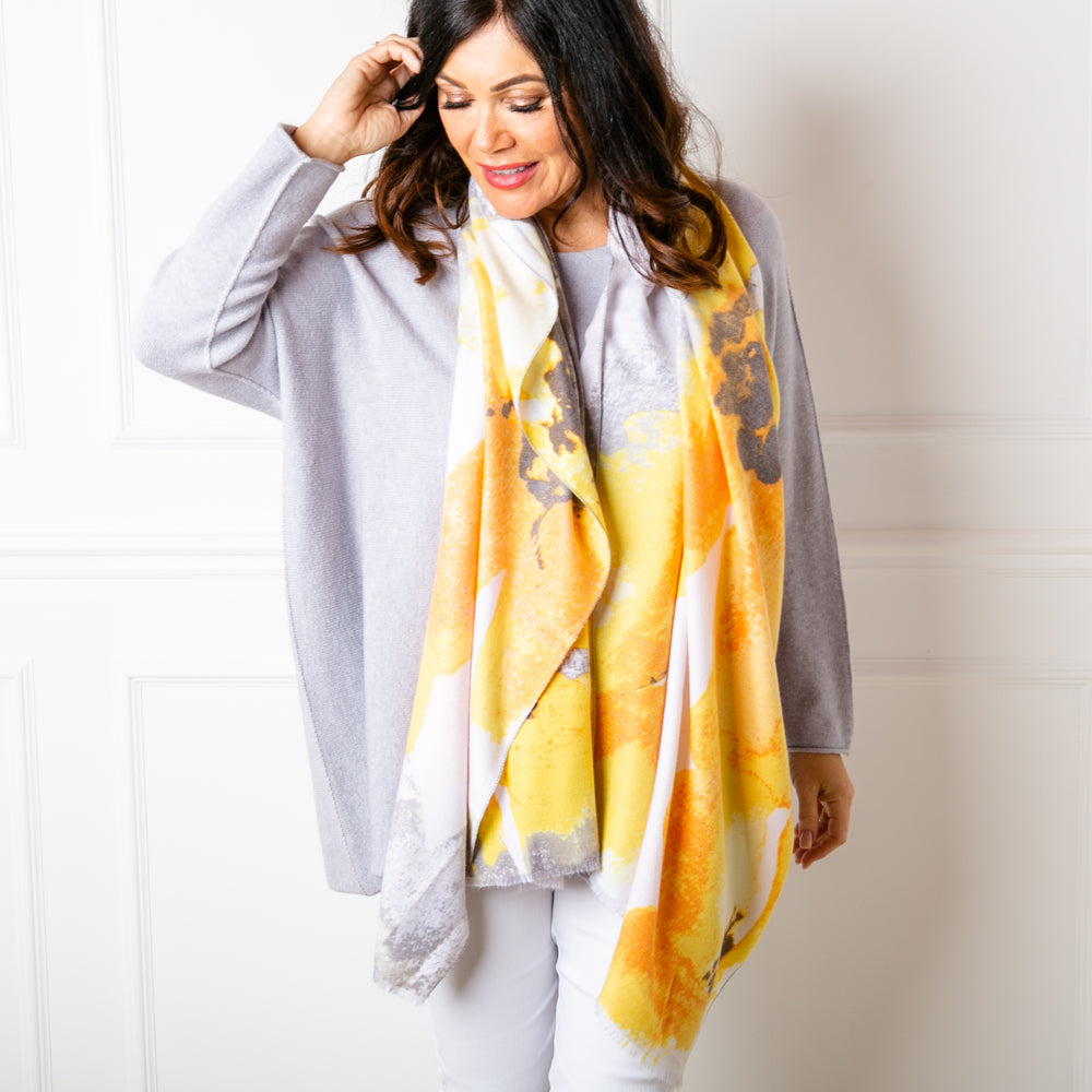 The Tokyo Scarf in yellow worn loosely around the models neck to show the floral pattern